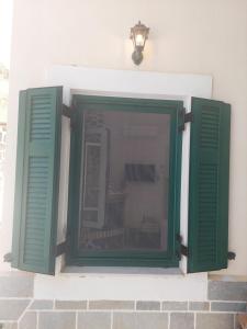 una finestra con persiane verdi su un edificio di Mesa Vrisi a Karpathos