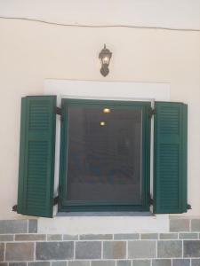 una finestra con persiane verdi su un edificio di Mesa Vrisi a Karpathos