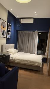 a bedroom with a white bed with a blue wall at Guangzhou YuXiang Apartment - Guangzhou Pazhou International Convention and Exhibition Center in Guangzhou