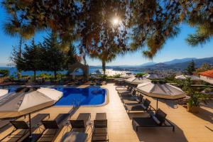 a swimming pool with umbrellas and lounge chairs with a view at Manastir Hotel & Suites in Bodrum City