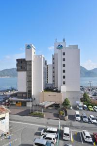 een parkeerplaats met auto's voor gebouwen bij Miyajima Coral Hotel in Miyajima
