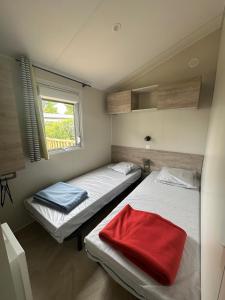 - 2 lits dans une petite chambre avec fenêtre dans l'établissement Camping le Moulin de la Salle, à Les Sables-dʼOlonne