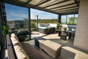 d'une terrasse avec un canapé et une baignoire sur un balcon. dans l'établissement Seaside residence - Sunset Appartement, à Kožino