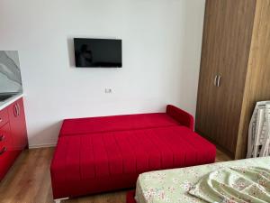 un sofá rojo en una habitación con TV en Suite Rana Hedhun, en Shëngjin