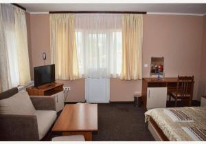 a living room with a couch and a television and a bed at Family Hotel Miglena in Govedartsi
