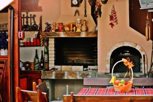 a kitchen with a fireplace with a table with a basket of fruit at Family Hotel Miglena in Govedartsi