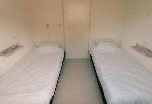 2 Betten in einem kleinen Zimmer mit weißen Wänden in der Unterkunft Rekerlanden 275 in Warmenhuizen