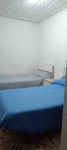 2 camas con sábanas azules en una habitación en Hospedaje El Paseo, en Cocentaina