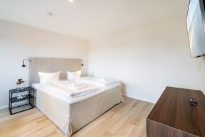 um quarto com uma cama branca e piso em madeira em Villa Albus App 7 em Ahlbeck