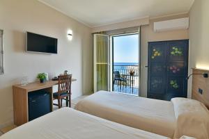 a bedroom with two beds and a desk and a balcony at Hotel & Apartments Villa Linda in Giardini Naxos