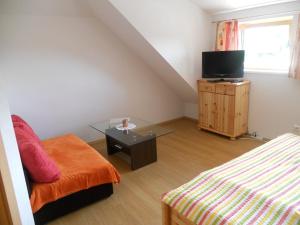 um quarto com uma cama, uma mesa e uma televisão em Landhaus Ebner em Millstatt