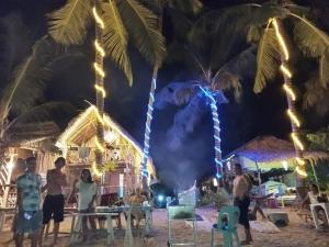 een groep mensen die 's nachts op het strand staan bij 8 Star Paradise in Locaroc