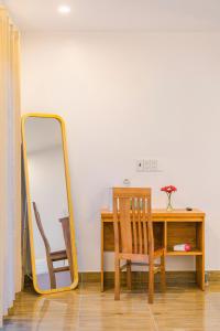 um espelho sentado ao lado de uma secretária com uma cadeira em VX Hotel em Da Lat