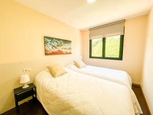 Dos camas en una habitación con ventana. en Apartamento Pindo B3 by ALÔGA, en O Pindo