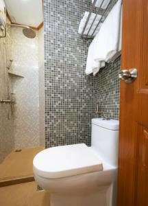 a bathroom with a toilet and a tiled wall at Beach Breeze and Spa in Hulhumale