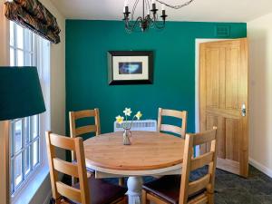 una mesa de comedor con sillas y una pared verde en Ardross, en Comrie