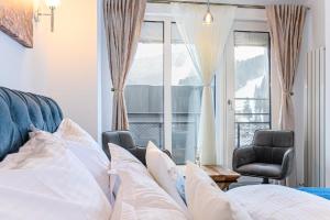a bedroom with a bed and a chair and a window at AYASI Luxury Apartment Predeal in Predeal