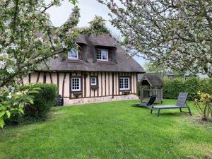 a house with a table and a chair in the yard at Le Pressoir de Bigard - chaumière normande - 8 personnes in Campigny
