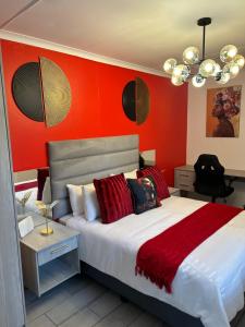 a bedroom with a large bed with red walls at SiBella guest house in Bloemfontein