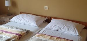 a bedroom with two beds with white sheets and pillows at Berci Villa in Balatonboglár