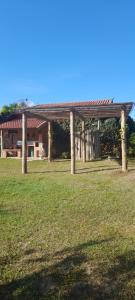 un pavillon en bois dans un champ avec une maison dans l'établissement Recanto das Flores, à São Thomé das Letras