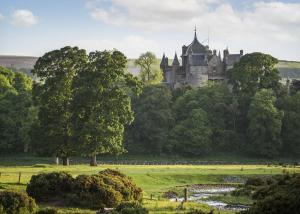 a castle sitting on top of a lush green field at Thirlestane Woodland Lodges in Lauder