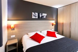 a bedroom with a bed with two red pillows at GLASSY HOTEL, The Originals City, Marne-la-Vallée Est, Meaux in Meaux