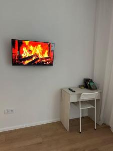 a room with a desk with a fire painting on the wall at Cozy Urban Retreat in Prigorodnyy
