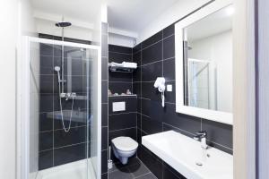 ein Badezimmer mit Toilette, Waschbecken und Spiegel in der Unterkunft The Originals City, Marne-la-Vallée Est, Meaux ,GLASSY HOTEL in Meaux