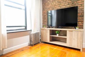 a living room with a television and a brick wall at New York Stylish 2BR Apartment in Manhattan in New York