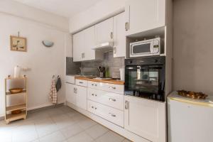 una cucina con mobili bianchi e un forno a microonde di Le Pastel Riverside Centre historique proche des plages ad Agde