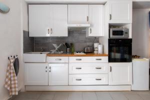 una cucina bianca con mobili bianchi e un lavello di Le Pastel Riverside Centre historique proche des plages ad Agde