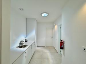 a white kitchen with a sink and a mirror at Feelgood Homestay Sagres in Sagres