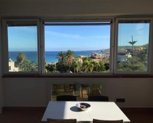 Il Grecale case vacanza في كروتوني: طاولة وكراسي في غرفة بثلاث نوافذ