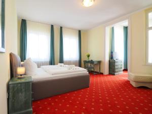 a bedroom with a bed and a desk and windows at Hotel See-Eck in Heringsdorf