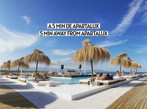 a pool with straw umbrellas and people sitting around it at Apartalux Aqua Sol in Grao de Castellón
