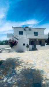 a large white house with a stone yard at Guesthouse Dollomaja Ksamil in Ksamil