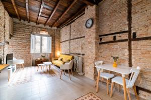 een woonkamer met een bakstenen muur en een tafel en stoelen bij Ma&to Alhóndiga Apart in Granada