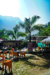 a group of tables and chairs and palm trees at The Family and Friends Resort Rishikesh in Rishīkesh