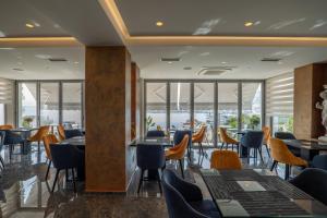a restaurant with tables and chairs and windows at Hotel Teuta in Sarandë