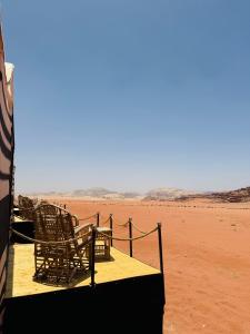 un gruppo di sedie seduti su una piattaforma nel deserto di Desert Bedouin adventure a Wadi Rum