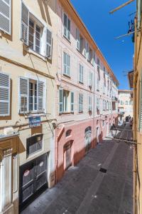 une ruelle vide avec un bâtiment rose dans une rue dans l'établissement Menton Old Town, à Menton