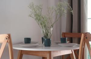 a white table with two plates and a vase with flowers at Onar House I in Achladies