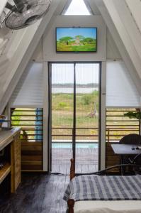 Habitación con ventana grande y TV en la pared. en Cashaw Cabin - Private A-frame Treasure Beach en Treasure Beach