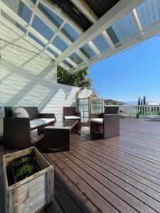 a wooden deck with chairs and a pergola at Island life! 2,5 bedroom house. in Vigra