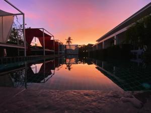 an empty swimming pool with a sunset in the background at Phangan Hometown Resort - Adults Only in Baan Tai