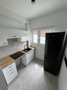 a kitchen with white cabinets and a black refrigerator at Mallborro - Z widokiem na zamek in Malbork