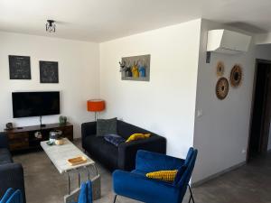 ein Wohnzimmer mit einem Sofa, Stühlen und einem TV in der Unterkunft Près colmar 6 