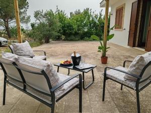 três cadeiras e uma mesa com uma tigela de fruta num pátio em Villa Petra em Botrugno