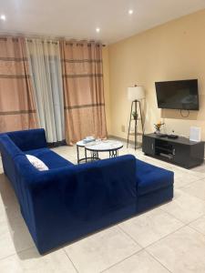 a blue couch in a living room with a tv at Avant Garde Luxury Apartment in Accra